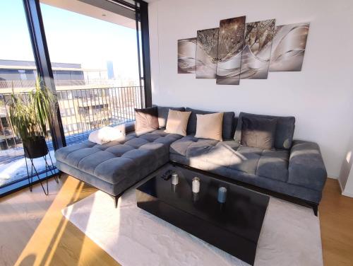 sala de estar con sofá y ventana grande en Panorama Apartment Vienna - free parking, sauna & fitness, en Viena
