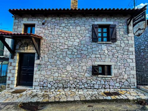 a stone building with windows and a clock on it at Guesthouse Armakas in Kalavrita