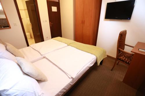 a hotel room with two beds and a television at Rustika Sobe in Osijek