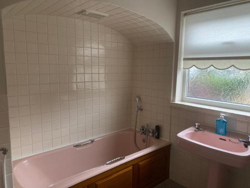 a bathroom with a pink tub and a sink at Bexleyhealth Town Center 5 Bedroom Luxurious Home in Bexleyheath