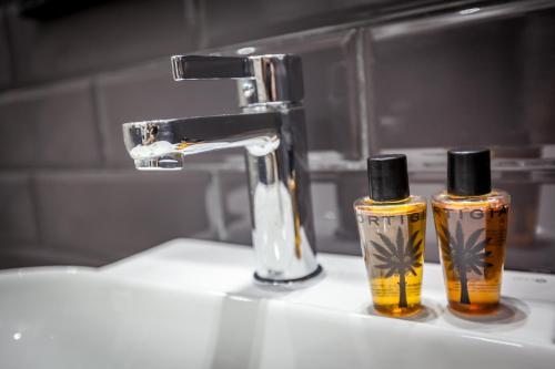 dos botellas de odorizantes sentadas en el lavabo del baño en Hotel Bologna, en Génova
