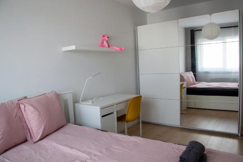 1 dormitorio con cama, escritorio y espejo en FLH - Pink Panther, en Sibiu