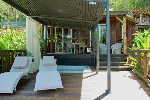 a porch with white chairs and a house at Le Domaine du Rocher Noir in Pointe-Noire