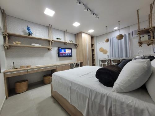een slaapkamer met een bed, een bureau en een televisie bij Flat Amarilis Apartamento 103 in Riviera de São Lourenço