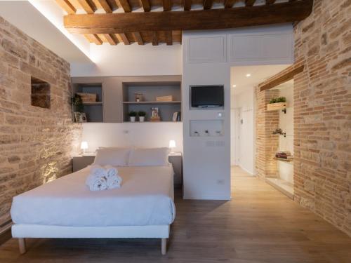 1 dormitorio con cama blanca y pared de ladrillo en Residenza Donna Iohanna, en Gubbio