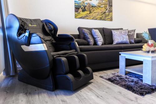 a large blue reclining chair in a living room with a couch at Relax-Apartment mit Indoor-Pool, Sauna, Massagesessel und Netflix in Schonach