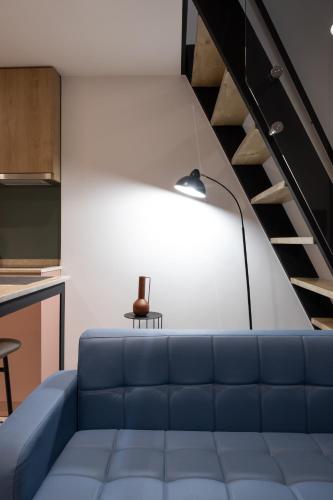 a living room with a blue couch and a staircase at Spa & Pool - Studio Apartments 365 in Tirana