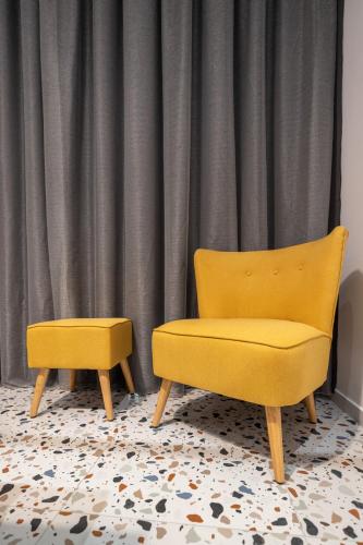 two yellow chairs in front of a curtain at Spa & Pool - Studio Apartments 365 in Tirana