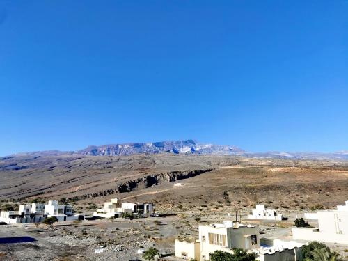 a view of a desert with white buildings and mountains at 228Hostel in Al Ḩamrāʼ