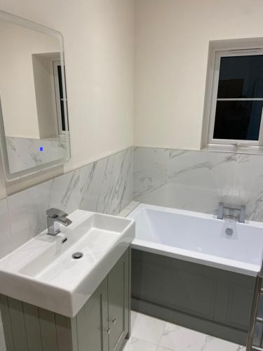 a white bathroom with a sink and a tub at The Lodge in Coltishall