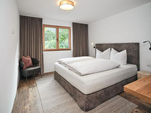 a bedroom with a large bed and a chair at Alpenchalet S´Andalr in Pfunds