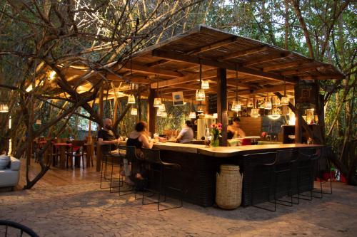 a bar with people sitting at a table in an outdoor restaurant at Hotel Noga in Zipolite