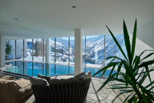 a living room with a pool and a chair and a plant at Alpenhotel Laurin in Hochgurgl