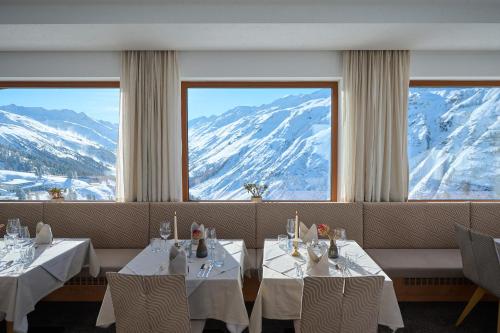 a restaurant with two tables and snow covered mountains at Alpenhotel Laurin in Hochgurgl