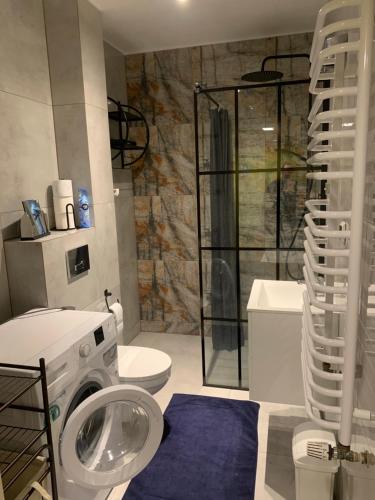 a bathroom with a shower and a washing machine at Apartament Na Wydmie - parter in Ustka