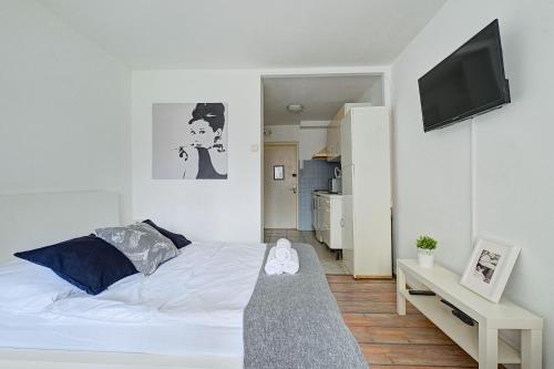 a white bedroom with a bed and a flat screen tv at Noctis Apartment Bagno in Warsaw