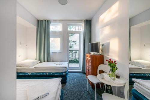 a hotel room with two beds and a table at Willa Albatros Happy Hours in Gdańsk