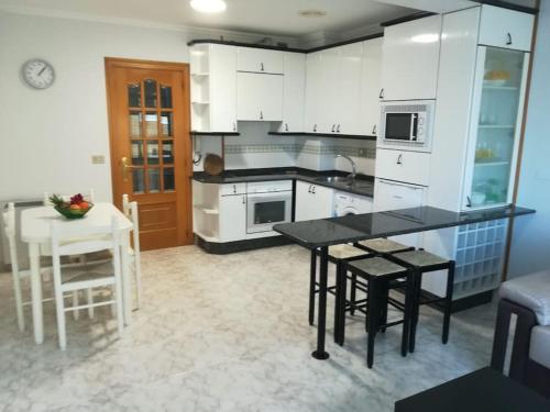 een keuken met witte kasten en een tafel en stoelen bij Apartamento Valleron in Foz
