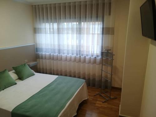een slaapkamer met een bed en een raam met gordijnen bij Apartamento Valleron in Foz