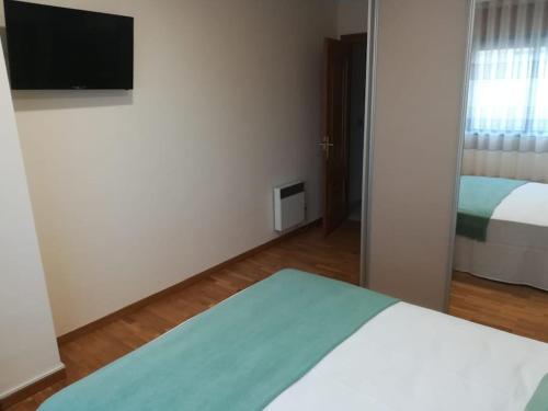 een slaapkamer met een bed en een televisie aan de muur bij Apartamento Valleron in Foz