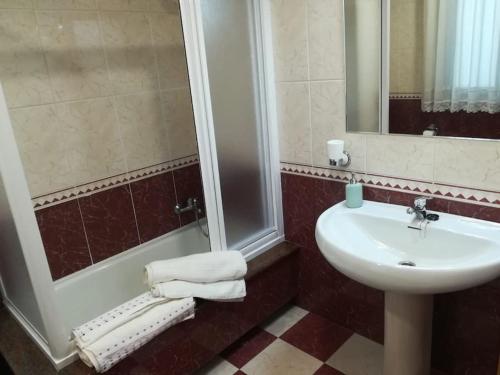een badkamer met een wastafel en een douche met handdoeken bij Apartamento Valleron in Foz