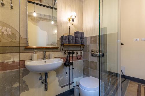 a bathroom with a sink and a toilet and a shower at Ladiri - Antica dimora in terra cruda in Sìnnai