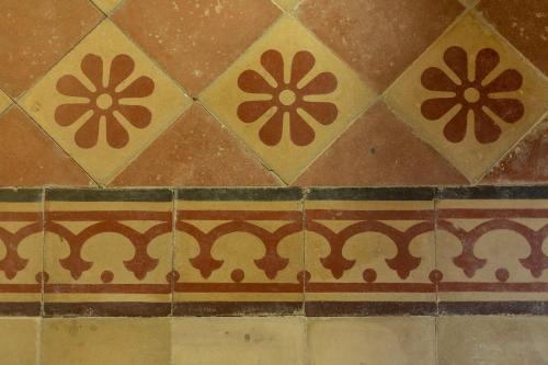 a tiled floor with brown and yellow designs on it at Ladiri - Antica dimora in terra cruda in Sìnnai