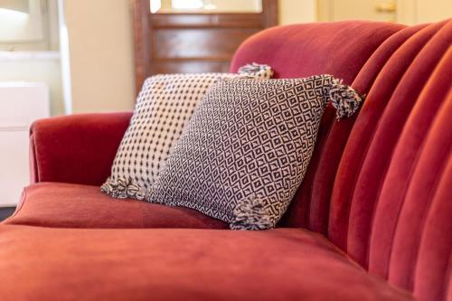 a red couch with two pillows on it at Ladiri - Antica dimora in terra cruda in Sìnnai