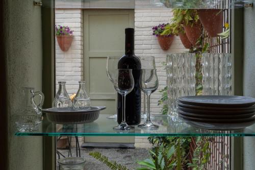 a glass table with a bottle of wine and glasses at Ladiri - Antica dimora in terra cruda in Sìnnai