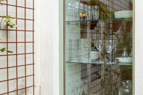 a glass shelf with plates and glasses on it at Ladiri - Antica dimora in terra cruda in Sìnnai