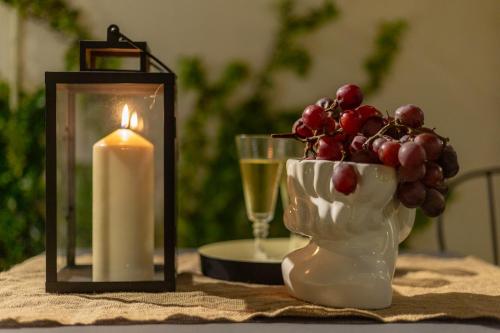 a candle and a vase with grapes and a glass of wine at Ladiri - Antica dimora in terra cruda in Sìnnai