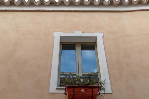 a window on the side of a building with a plant at Ladiri - Antica dimora in terra cruda in Sìnnai