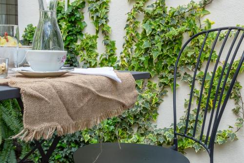 a table with a vase and a chair next to a ivy wall at Ladiri - Antica dimora in terra cruda in Sìnnai