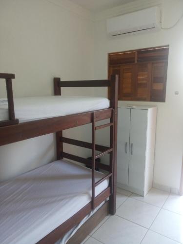 a room with two bunk beds and a refrigerator at Casa do Mochileiro Airport Hostel & Pousada in São Gonçalo do Amarante