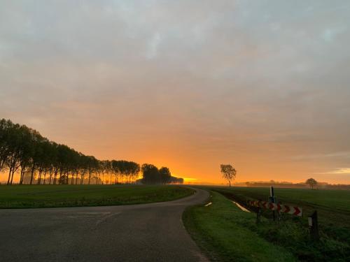 an empty road with the sunset in the background at Vakantie-woning in Sint Kruis