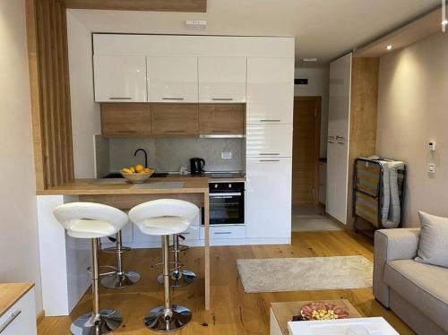 cocina con armarios blancos y taburetes en la sala de estar en Jellenaa, en Zlatibor