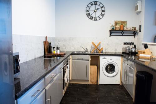 a kitchen with a washing machine and a clock on the wall at Characterful Abode with FREE parking. in Liverpool