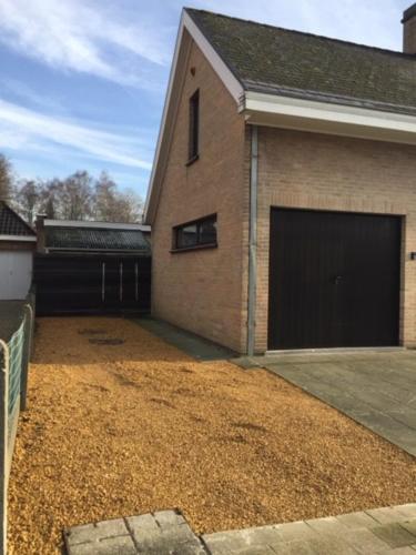 a house with two garage doors and a dirt yard at Maison de Marcel Big house near centre free parking in Bruges
