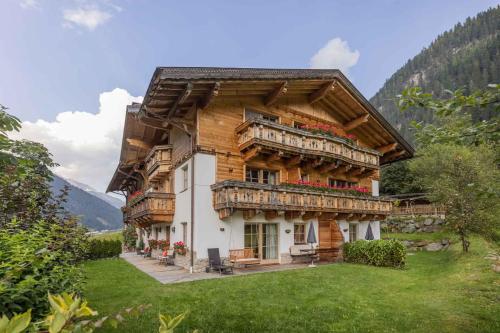 a large wooden house with a balcony in the grass at Landhaus Wildes Wasser in Neustift im Stubaital
