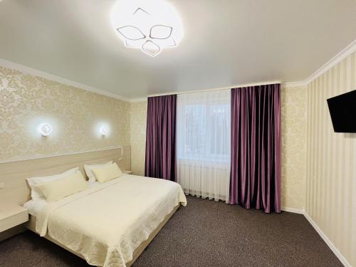 1 dormitorio con cama blanca y ventana en Готель Лаванда, en Khmelʼnytsʼkyy