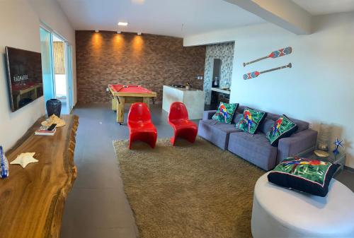 a living room with a couch and two red chairs at Tabubinha Paradise in Beberibe