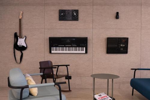 a living room with a chair and a guitar on a wall at ibis Styles Nancy Centre Gare in Nancy