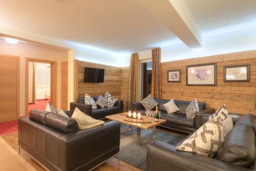 a living room with leather couches and a tv at Chalet Gamskar in Sankt Anton am Arlberg