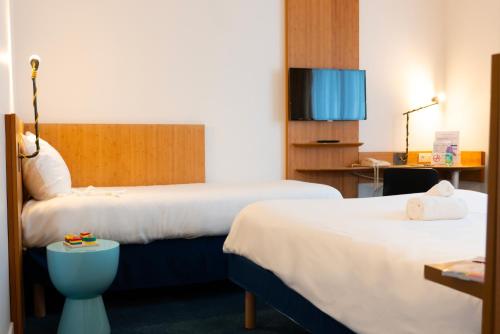 una camera d'albergo con due letti e un tavolo di ibis Styles Nancy Centre Gare a Nancy