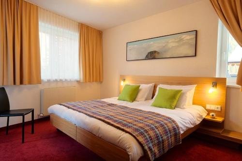 a hotel room with a large bed with green pillows at Chalet Gamskar in Sankt Anton am Arlberg
