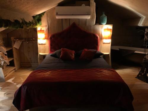 a bedroom with a red bed with two lamps at Boutique Cottage - Sauna and Jacuzzi - El Clandestino in Érezée