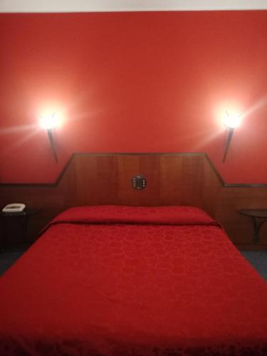 a red bedroom with a bed with two lights on the wall at Hotel Cangrande Di Soave in Soave