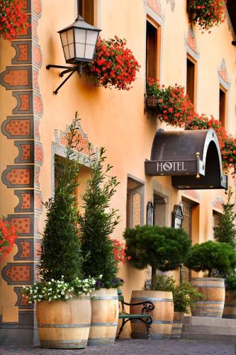 a bench in front of a building with potted plants at Hotel Cavallino D'Oro Bed&Breakfast in Castelrotto