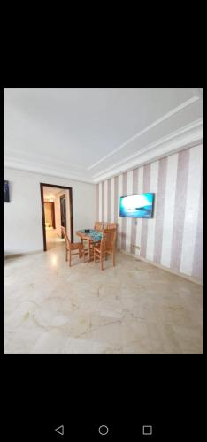a room with a table and chairs and a television at Résidence jnane California in Casablanca