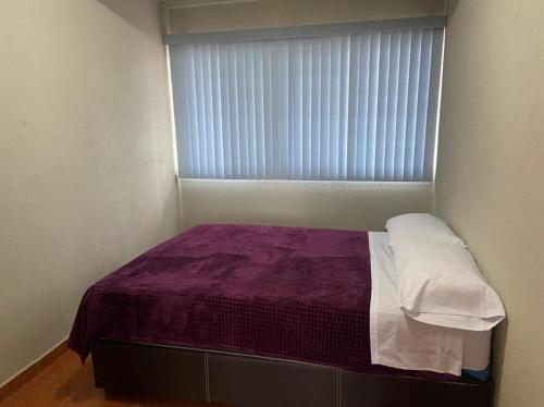 a small bed in a room with a window at Departamento con gran área verde in Zacatlán